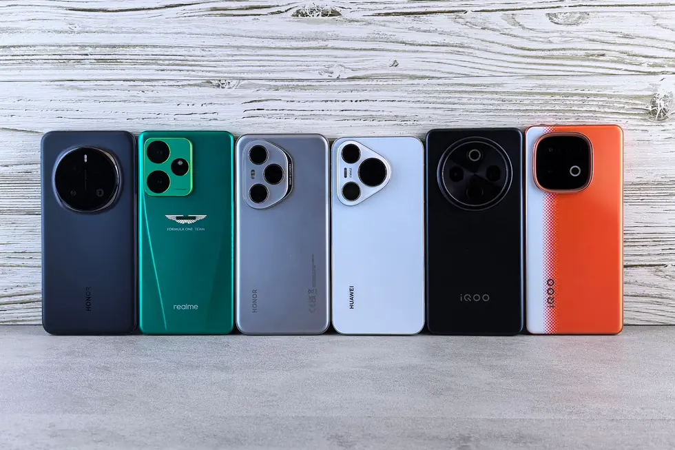 Six téléphones posés dos visible contre un mur en bois